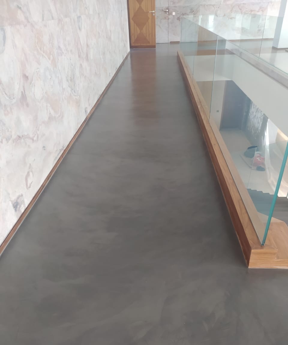 "Un corridor contemporain aux murs en marbre veiné, doté d’un sol en béton ciré gris foncé et d’une balustrade en verre transparent pour une ambiance lumineuse et élégante
