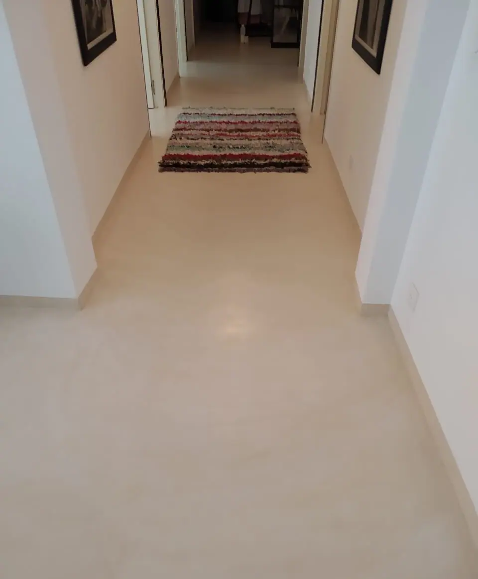 Un corridor moderne aux murs blancs, doté d’un tapis coloré à motifs géométriques au centre, offrant une touche de confort et de style dans un espace minimaliste.