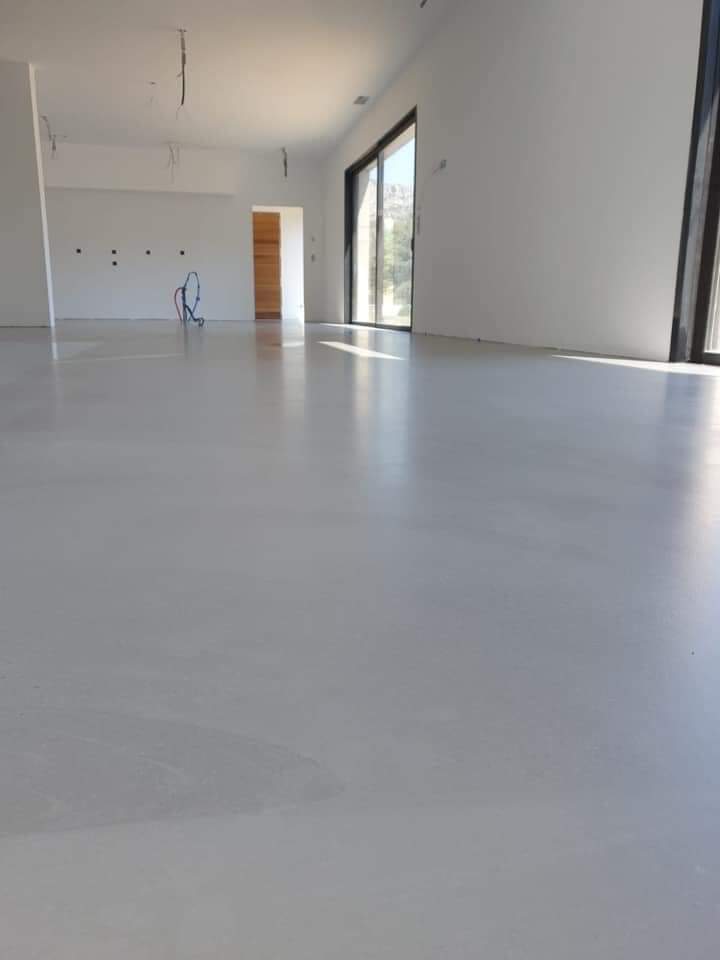 salon avec sol en béton ciré blanc brillant et de fenêtres grandes pour une lumière naturelle abondante