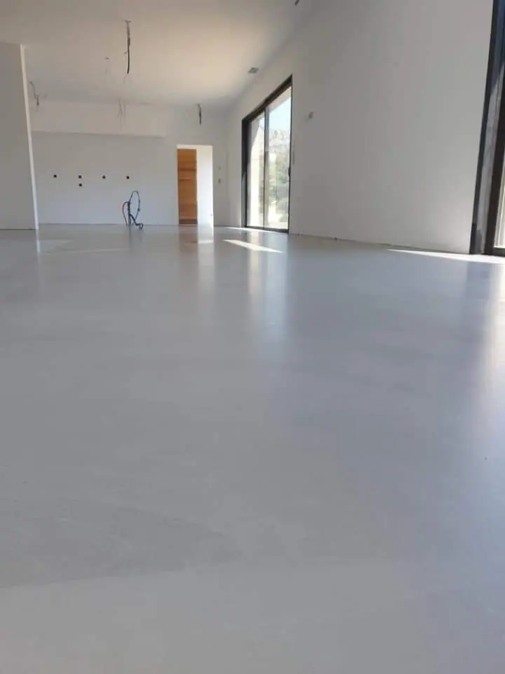 salon avec sol en béton ciré blanc brillant et de fenêtres grandes pour une lumière naturelle abondante